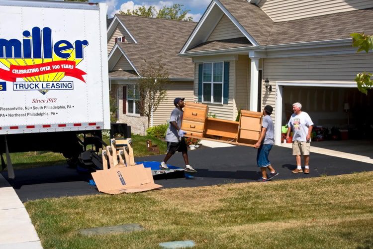 Two guys carrying a desk of a senior man who is moving houses