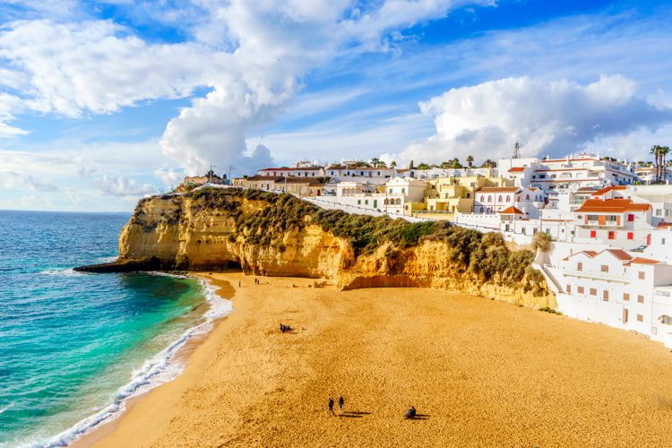 Sandy beach between cliffs and white architecture in Carvoeiro, Algarve, Portugal