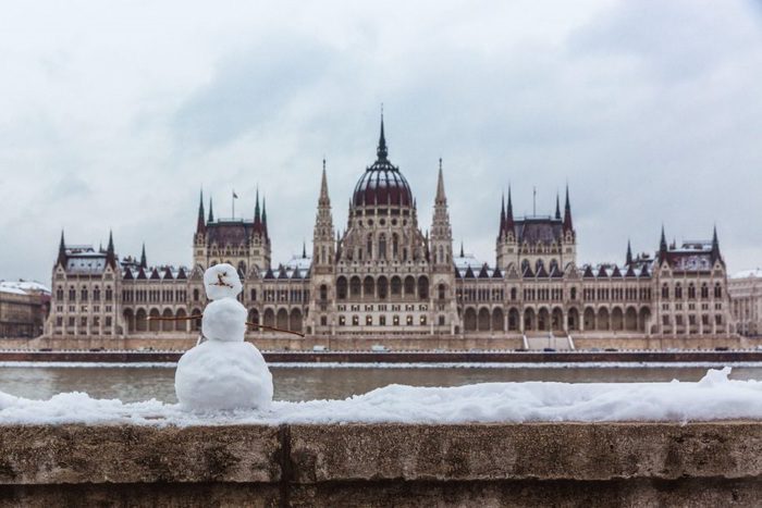 Hungarian parliament building at winter with snow. Snowman on the river bank