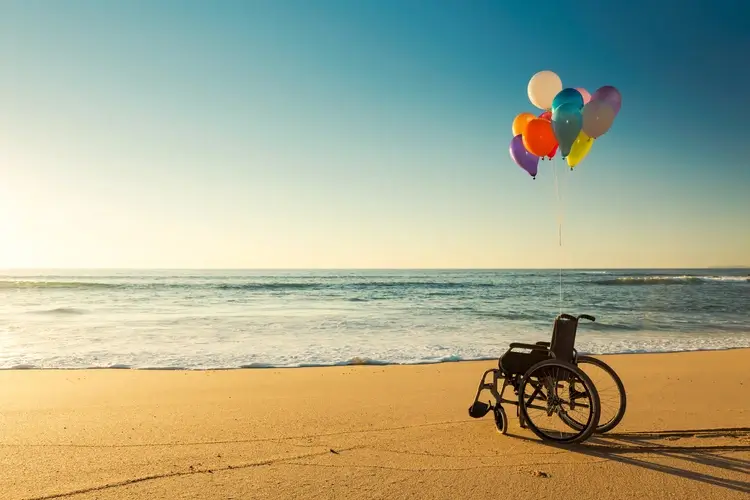 Wheelchair with tied ballon on the beach
