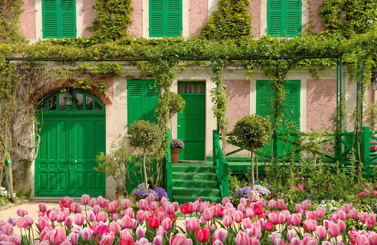 House with green doors and garden with flowers