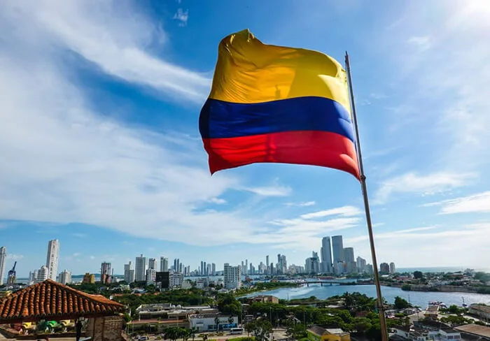 A Colombian flag flying with city in the backround. comparing panama and colombia