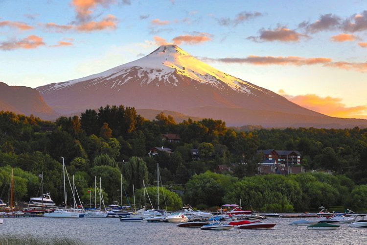 A lake with jet skies and boats in Pucon, Chile with the Villa Rica volcano on the background during sunset