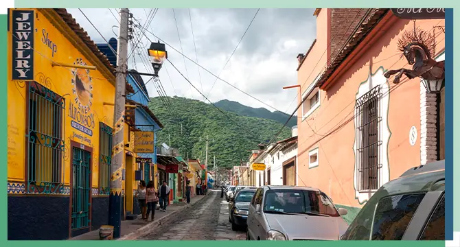 A small street with parked cars and colorful buildings in Ajijic, Mexico