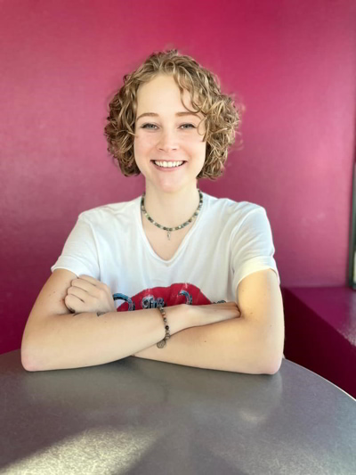Gabrielle Wells sitting on a restaurant with a pink wall