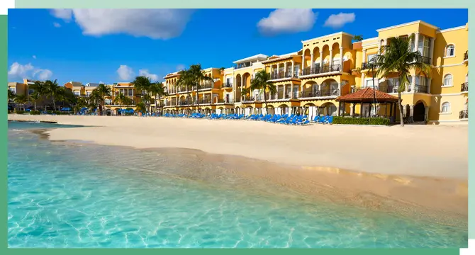 Clear waters and white sand in Playa del Carmen, Mexico with a yellow building on the back