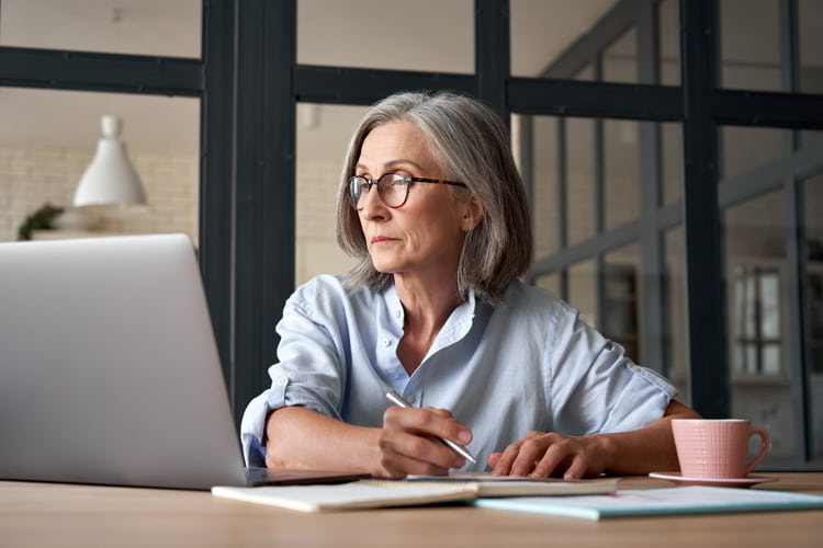 Older woman watching training webinar on laptop working from home