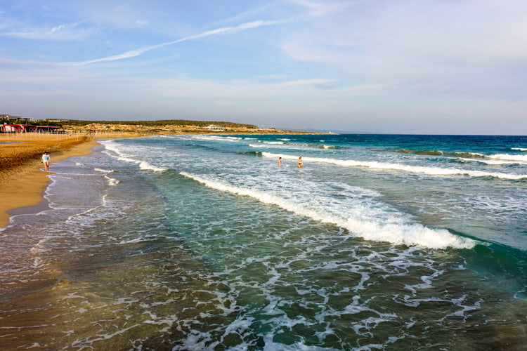 People enjoying the clear blue waters and sandy beach in Bafra, Cyprus