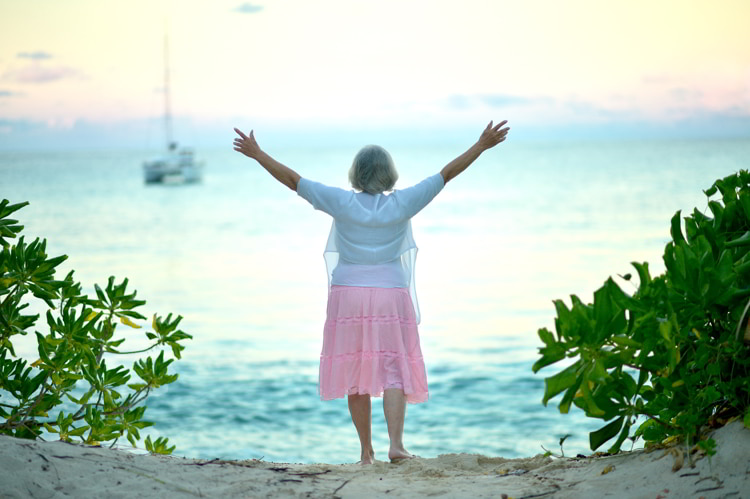 Senior woman with pink skirt and white shirt who retired alone at the beach