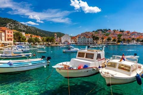 A bay with clear water, boats and buildings in the distance