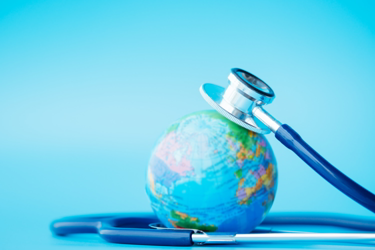 Stethoscope wrapped around globe on blue background.