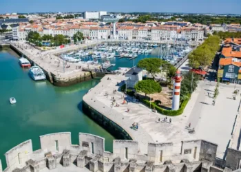 Aerial view of La Rochelle’s historic harbor in France, featuring its iconic towers, marina, and vibrant waterfront lined with cafés and boats.