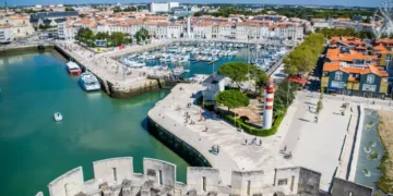 Aerial view of La Rochelle’s historic harbor in France, featuring its iconic towers, marina, and vibrant waterfront lined with cafés and boats.