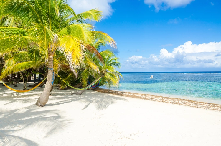Blue skies and sandy beach in Belize. Cheapest Places To Live In The Caribbean Rental Property