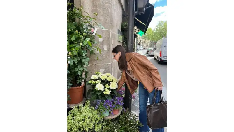 Kathleen exploring a charming Parisian street lined with flowers and greenery.