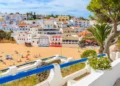 Promenade along street in Carvoeiro fishing village with view of colourful houses on beach, Algarve, Portugal
