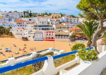 Promenade along street in Carvoeiro fishing village with view of colourful houses on beach, Algarve, Portugal