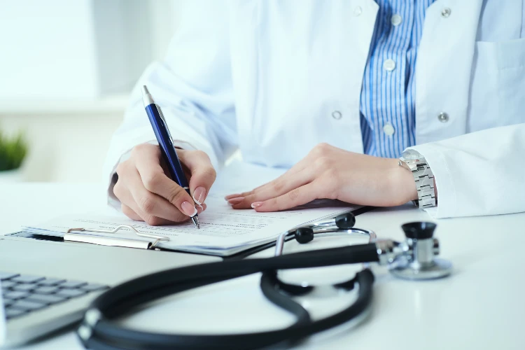 Mid section of female doctor writes prescription to patient at worktable