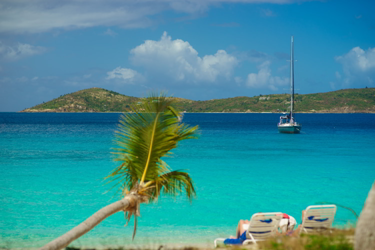 Relaxing on chair on the beach with palm and yacht on background