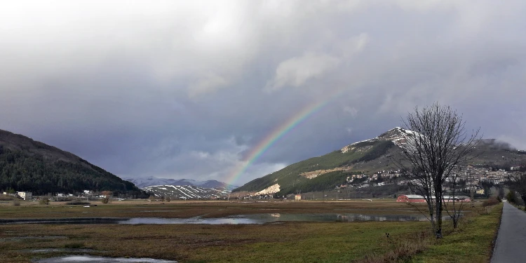 A rainbow on the plateau among the mountains under a cloudy gray sky, Roccaraso, Abruzzo, Italy