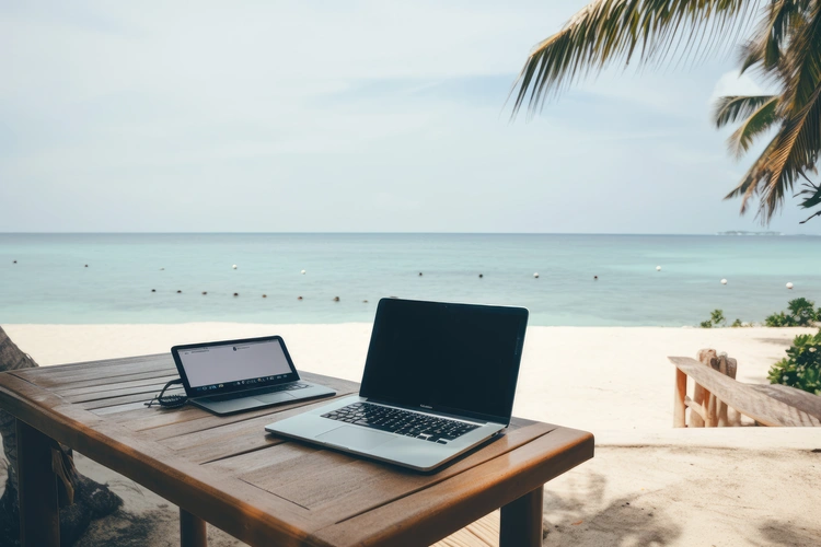 View from a desk and laptop with a palm tree and beach scene. Business Opportunities Abroad