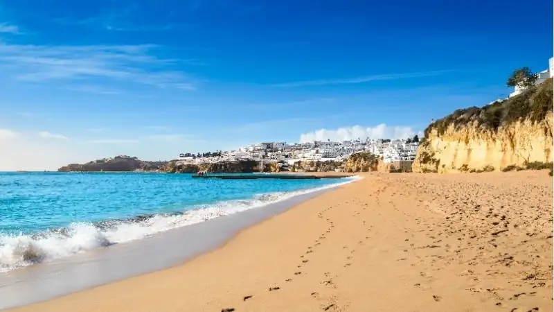 Golden sandy beach, turquoise waters, and dramatic cliffs along the Algarve coast in southern Portugal.