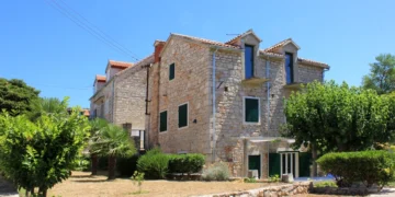 A stone house surrounded by trees in a sunny day