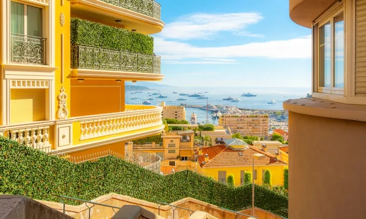 Benefits of overseas property showcased by luxury residential apartments, condos, and townhomes in the hills of Monte Carlo, Monaco, overlooking the Rock, Mediterranean Sea, and marina along the Riviera.