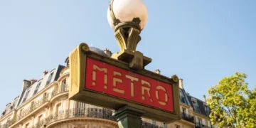 A traditional Paris Metro sign with buildings in the background. Europe Cities