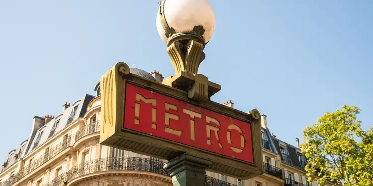 A traditional Paris Metro sign with buildings in the background. Europe Cities