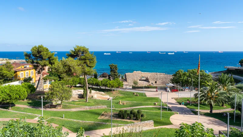 Roman Amphitheater and Coastal View, Tarragona Roman amphitheater by the Mediterranean Sea in Tarragona, surrounded by parks and palm trees