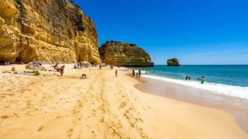 People relaxing and swimming at a sandy beach.
