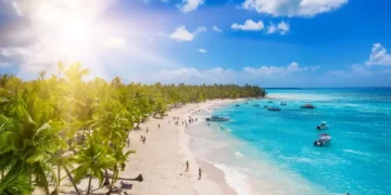 People enjoying a tropical Caribbean beach with white sands and clear waters. Cheapest Places To Live In The Caribbean