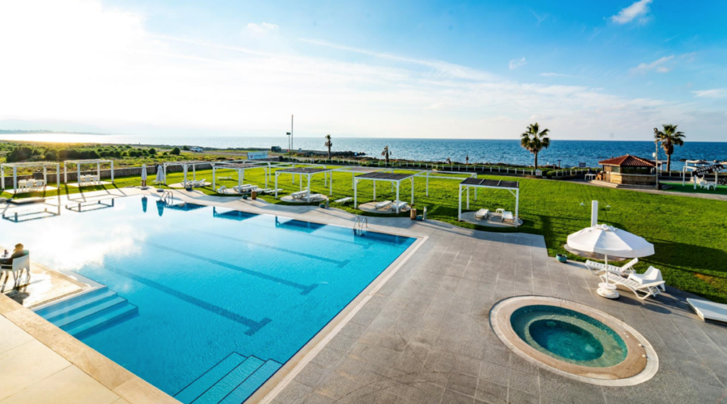 oceanfront resort scene featuring a large swimming pool and jacuzzi