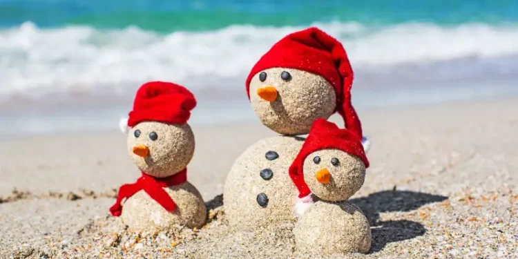 Snowmen family at sea beach in santa hats.
