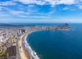 An aerial view of Mazatlán Beach on a sunny morning, showcasing the blue ocean's gentle waves meeting the sandy shores of this popular tourist destination