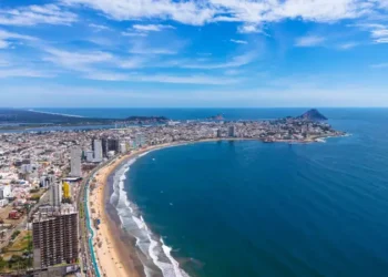 An aerial view of Mazatlán Beach on a sunny morning, showcasing the blue ocean's gentle waves meeting the sandy shores of this popular tourist destination