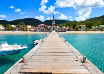 Wooden pier leading to a colorful coastal village with a church