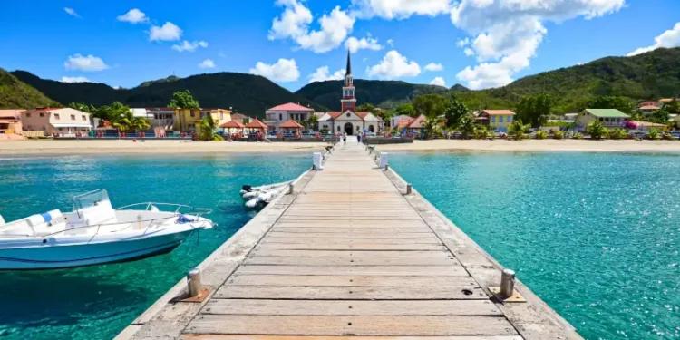 Wooden pier leading to a colorful coastal village with a church
