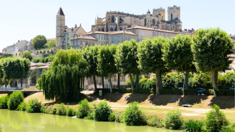 Picturesque summer landscape of French city of Auch overlooking Roman Catholic Cathedral and Armagnac Tower. View across Gers river
