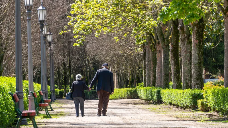 Elderly couple walking hand in hand through the Taconera Park. Pamplona