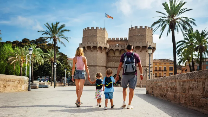 Parents with kids walk in front of famous Torres de Serrans, Valencia, Spain