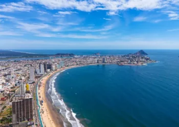 An aerial view of Mazatlán Beach on a sunny morning, showcasing the blue ocean's gentle waves meeting the sandy shores of this popular tourist destination