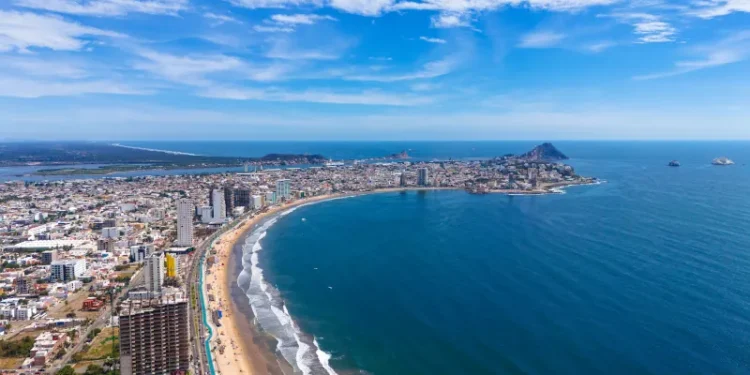 An aerial view of Mazatlán Beach on a sunny morning, showcasing the blue ocean's gentle waves meeting the sandy shores of this popular tourist destination