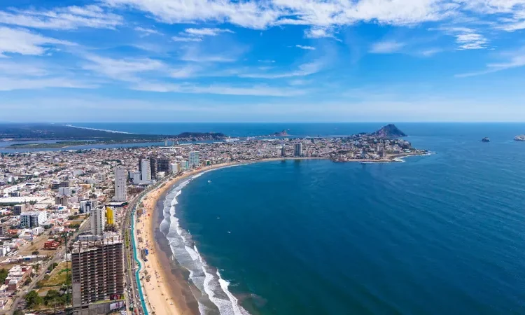 An aerial view of Mazatlán Beach on a sunny morning, showcasing the blue ocean's gentle waves meeting the sandy shores of this popular tourist destination