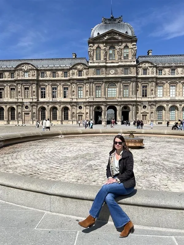 Kathleen Peddicord sitting by a fountain in the main courtyard of the Louvre Palace in Paris, France