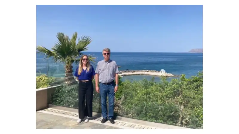 Sophia and Lief are standing side by side on a sunny seaside terrace.