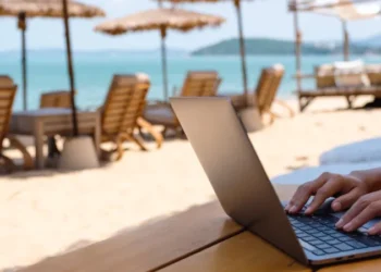 Closeup of a woman working and typing on laptop computer on the beach