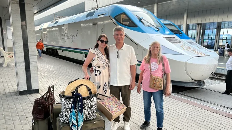 Kathleen Peddicord and Lief Simon Pose in fron of a train at the Tashkent Train Station Uzbekistan
