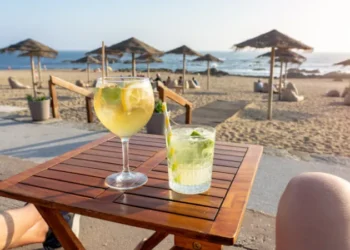 Woman enjoying a Porto tonic cocktail at a beach bar in Porto, Portugal